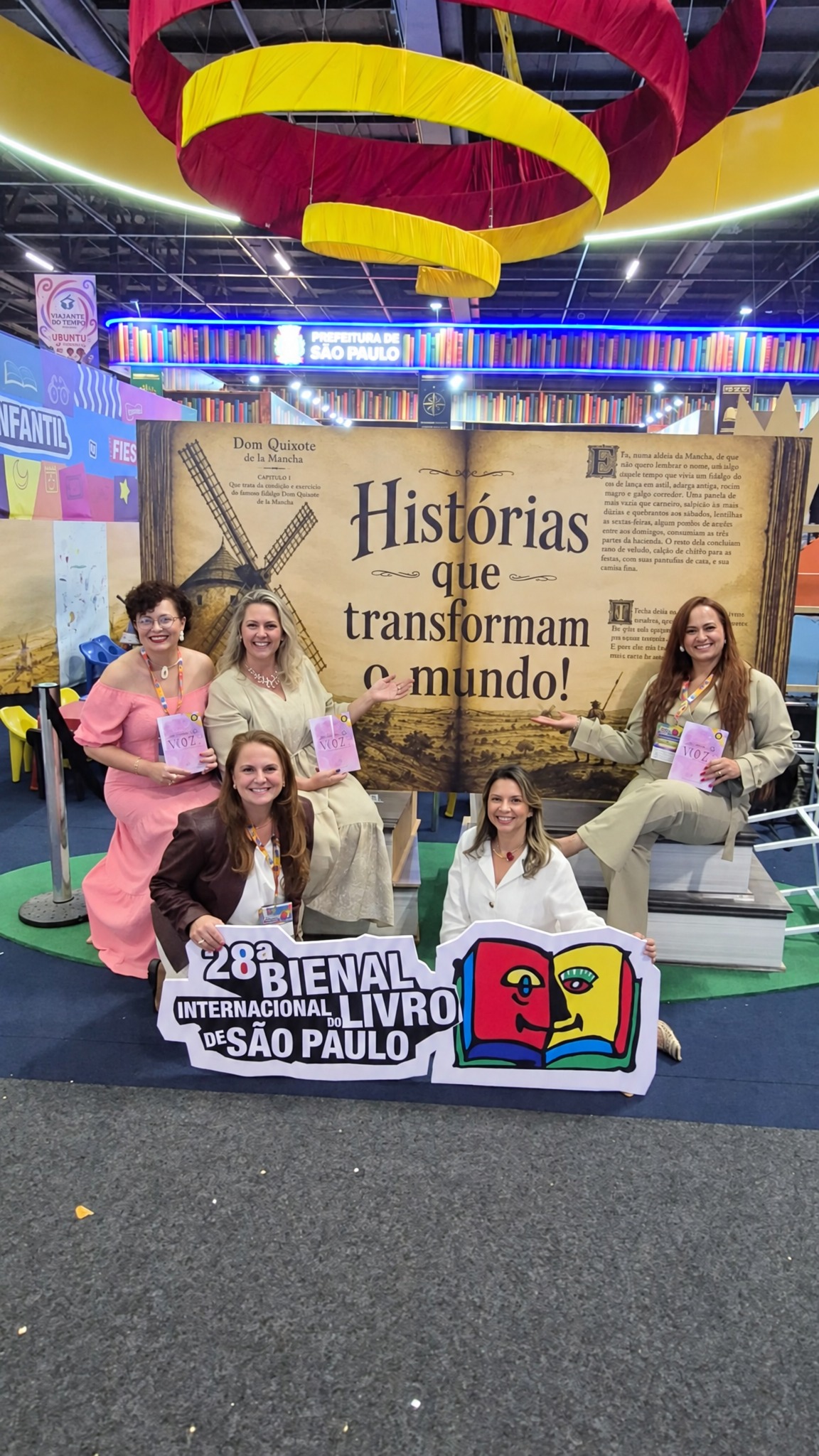 Grupo com placa "28ª Bienal Internacional do Livro de São Paulo — Histórias que transformam o mundo"