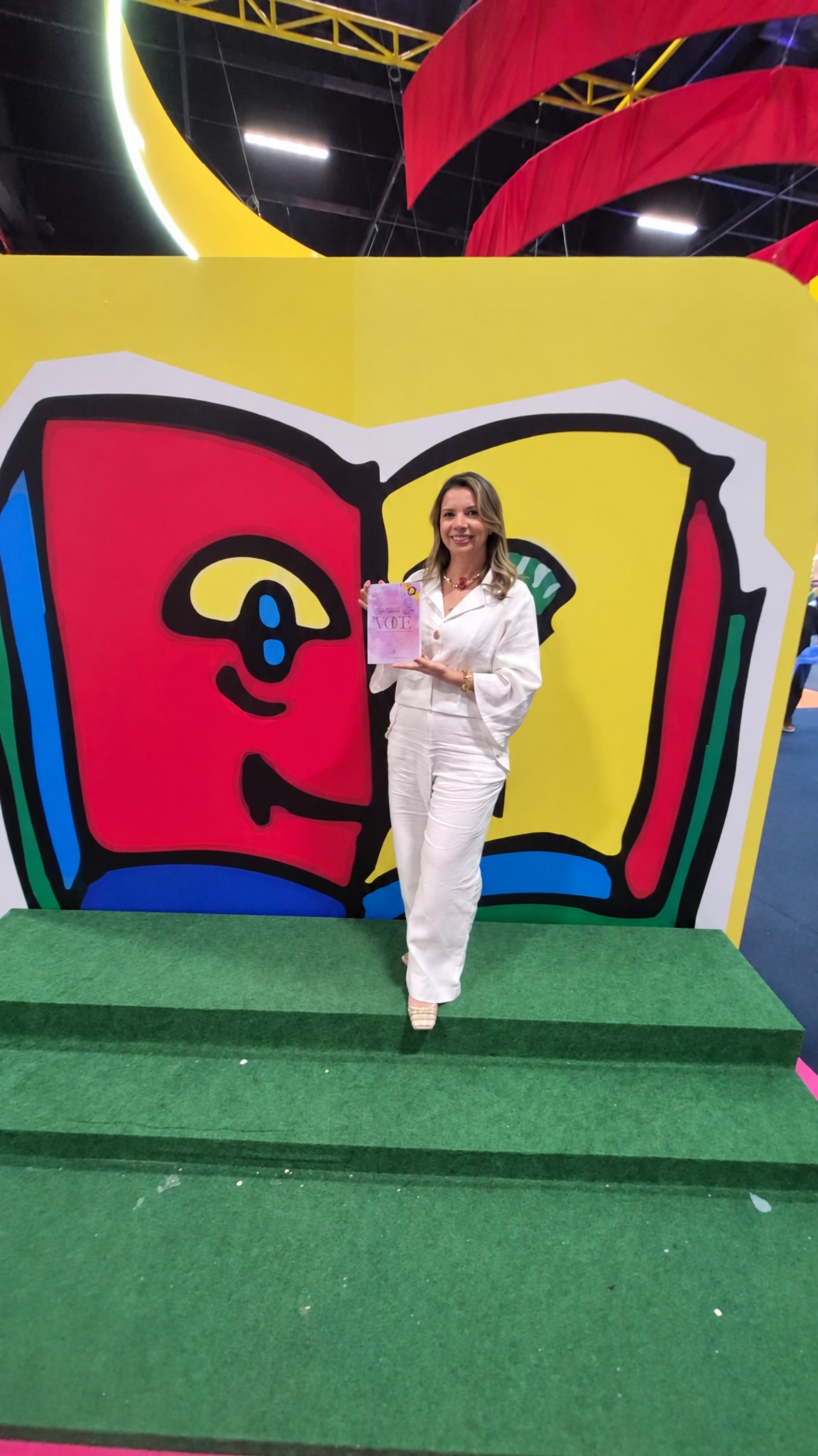 Autora com livro no cenário do livro gigante — 28ª Bienal