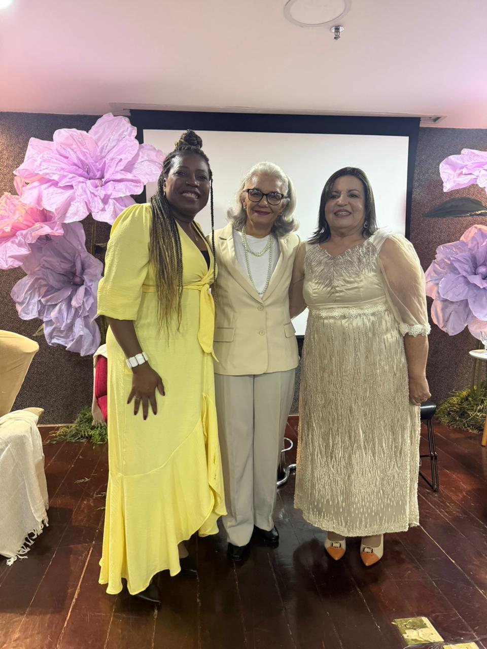 Três amigas posando juntas na decoração floral