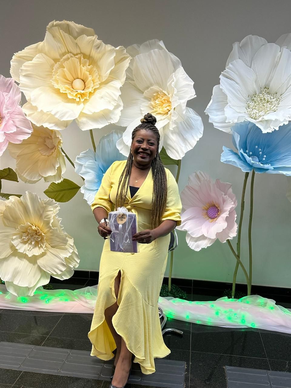 Cynthia Ferreira em frente ao painel de flores gigantes
